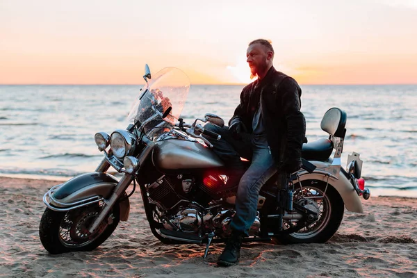 Gün batımında sahilde bir motorcu.