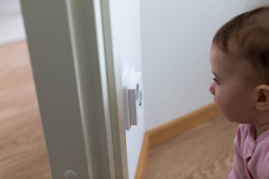 Küçük çocuk bir elektrik prizine evde arıyor. Çocukların güvenliği için