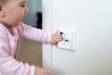 Küçük çocuk bir elektrik prizine evde dokunur. Çocukların güvenliği için