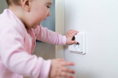 Küçük çocuk bir elektrik prizine evde dokunur. Çocukların güvenliği için