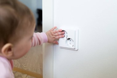 Küçük çocuk bir elektrik prizine evde dokunur. Çocukların güvenliği için