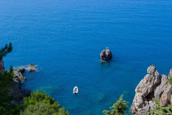 Korfu, Yunanistan kayalık sahil denizde küçük şişme bota.