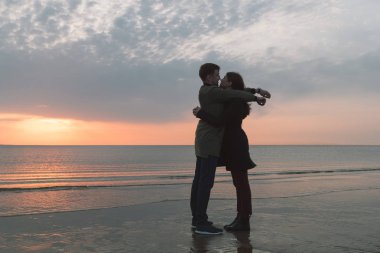 Genç çift üzerinde deniz kıyısı sonbaharda sarılma sevgi dolu