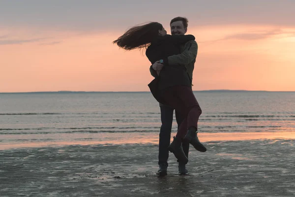Молодая любящая пара кружится на берегу моря осенью — стоковое фото