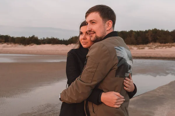 Молодая любящая пара, обнимающаяся на берегу моря осенью — стоковое фото
