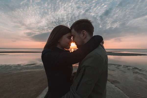 Jonge liefdevolle paar knuffelen op de kust-zonsondergang in de herfst — Stockfoto