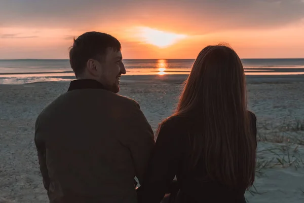 Jovem casal amoroso assistindo o pôr do sol no mar no outono . — Fotografia de Stock