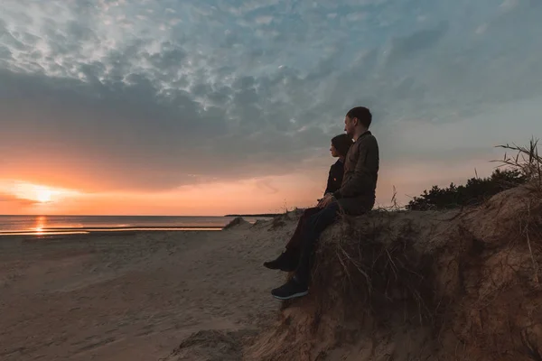 Jonge liefdevolle paar genieten van de zonsondergang op zee in de herfst. — Stockfoto