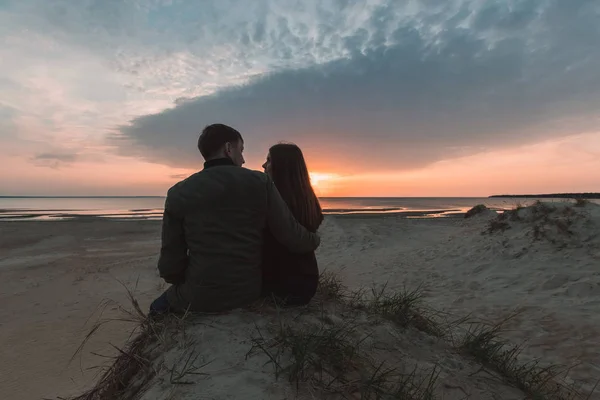 Joven pareja amorosa disfrutando de la puesta de sol en el mar en otoño . — Foto de Stock