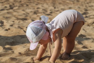 Küçük çocuk sahilde oynuyor.