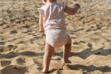 Küçük çocuk sahilde oynuyor.