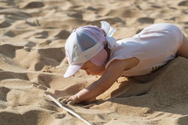 Küçük çocuk sahilde oynuyor.