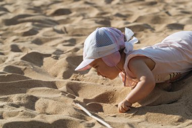 Küçük çocuk sahilde oynuyor.