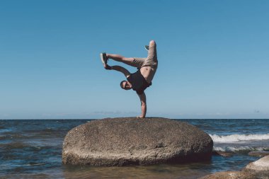 Güçlü adam bir taş bir arka plan bir koy ve gök poz.