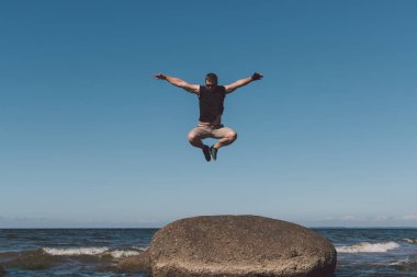 Güçlü adam bir taş bir arka plan bir koy ve gök poz.