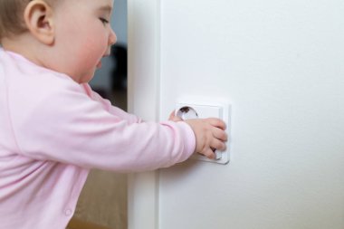 Küçük çocuk bir elektrik prizine evde dokunur. Çocukların güvenliği için