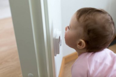 Küçük çocuk bir elektrik prizine evde arıyor. Çocukların güvenliği için