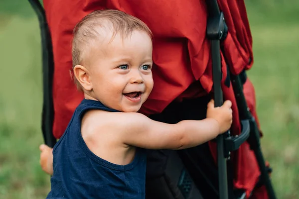 Little boy laughing near the stroller. — Stock Photo, Image