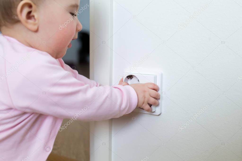 Small child touches an electrical outlet at home. Safety of children