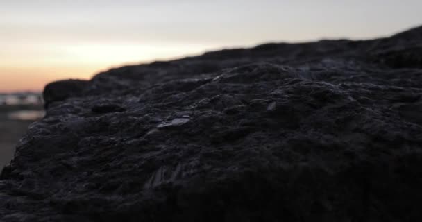 Великий камінь на морському пляжі на заході сонця . — стокове відео