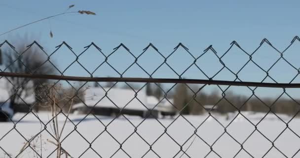 De mazen van het hek in het dorp in de winter. vloeiende bewegingen van rechts naar links — Stockvideo
