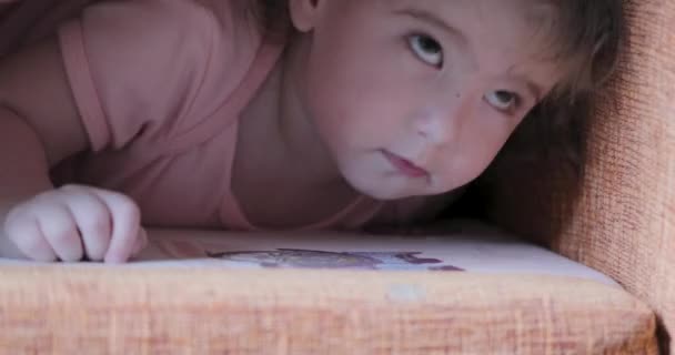 Маленькая девочка прячется под подушкой крупным планом — стоковое видео