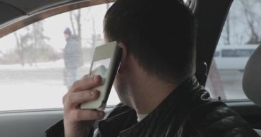 genç adam arabanın içinde otururken smartphone cep telefonu ile konuşmak