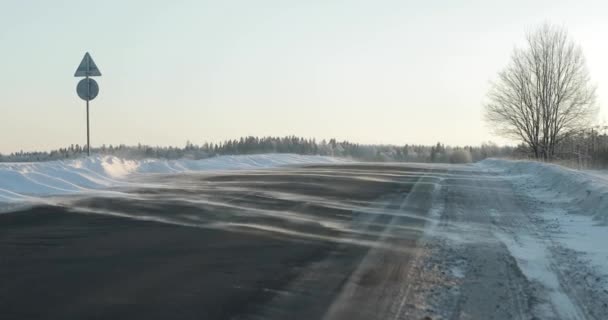 Vent soufflant la neige sur une route de campagne. hiver jour givré — Video