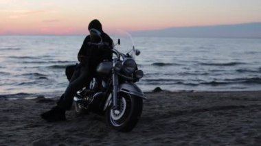 Motorcu motosikletçi akşam okyanus kıyısında