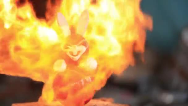 Enfants vieux lapin jouet en plastique fondu de la flamme chaude du feu. Vidéo au ralenti 