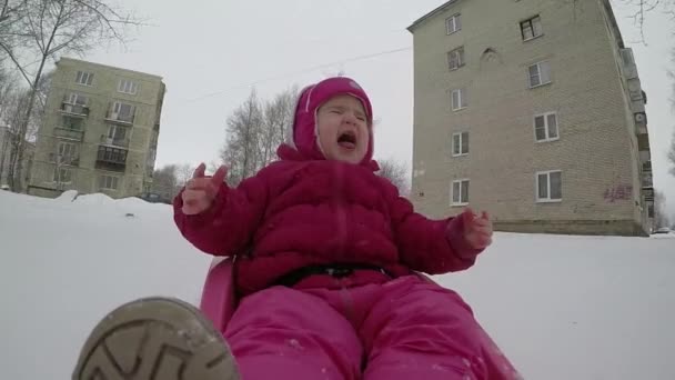 Jong kind glipt door de sneeuw op een slee in slow motion — Stockvideo