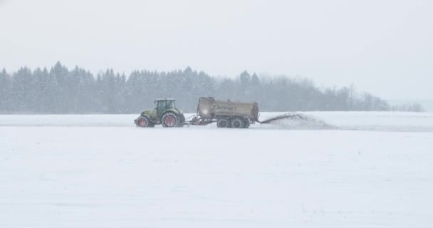 Сельскохозяйственный трактор удобряет поле зимой — стоковое видео