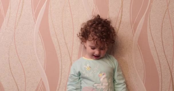 Petite fille bouclée souriante jetant des jouets en peluche à la maison au mur — Video