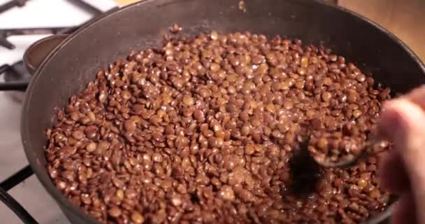 Roosteren in een koekenpan linze close-up. roeren met een lepel — Stockvideo