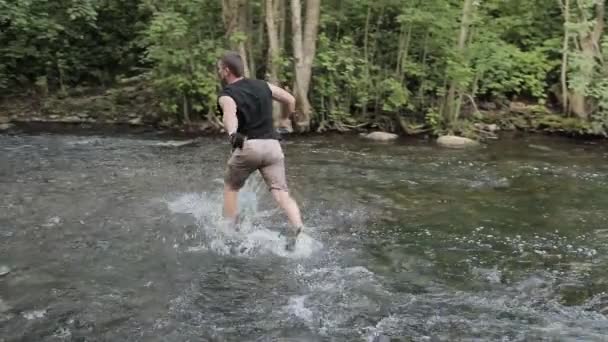 El hombre cruza el río corriendo. Movimiento lento — Vídeos de Stock
