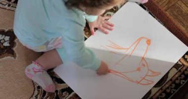 Katta oturan küçük kız çizer