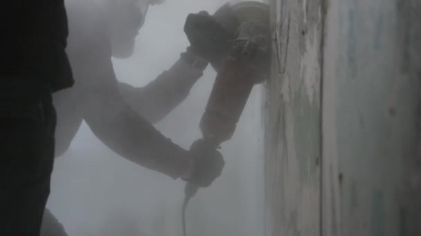 Homme scie un mur de béton avec une meuleuse d'angle. Vidéo au ralenti — Video