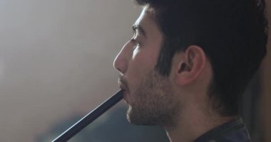 genç adam bir anız ile bir nargile sigara içiyor.