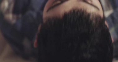 bir kıl olan genç adam kafasını arkaya doğru yatırır ve dışarı duman sağlar