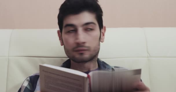 Jeune homme lit un livre et regarde autour de lui — Video