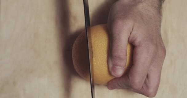 Naranja se corta con un cuchillo por la mitad — Vídeo de stock