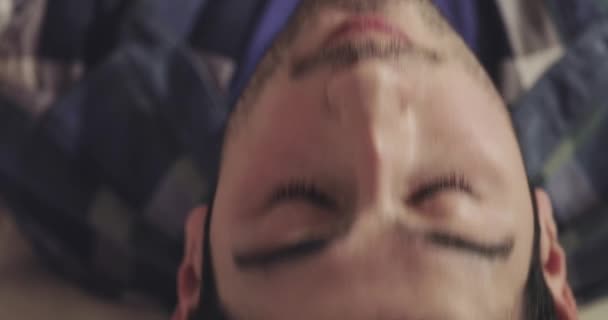 Молодой человек с щетиной наклоняет голову назад и выпускает дым — стоковое видео