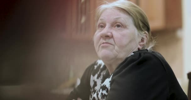 Старая бабушка рассказывает истории, сидя за столом — стоковое видео
