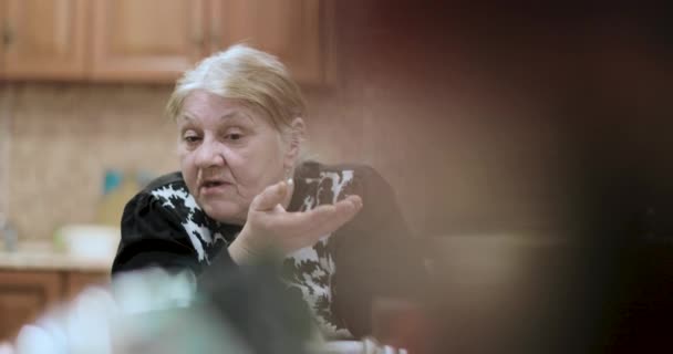 Vieille grand-mère raconte les histoires assis à la table — Video