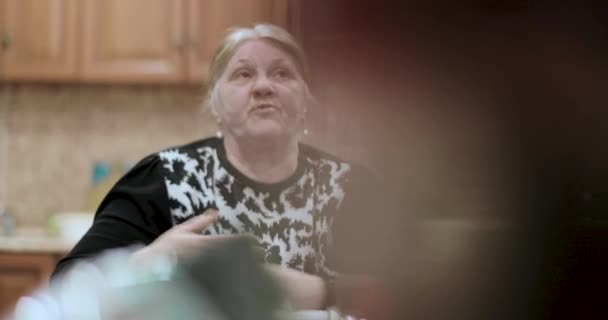 Old grandmother tells the stories sitting at the table — Stock Video