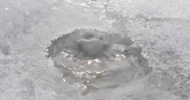 Drops of water fall and have already pierced the hole in the snow — Stock Video