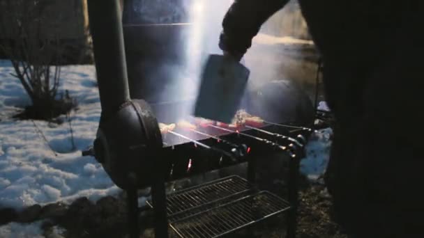 Aripile de pui sunt gătite la grătar și, în același timp, fluturând un accesoriu pentru a menține temperatura — Videoclip de stoc