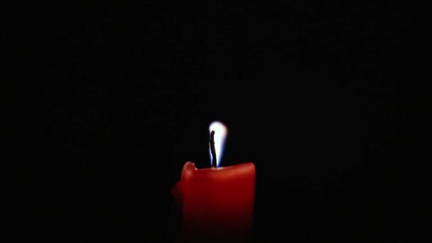 Red candle blows off the wind in the dark — Stock Video