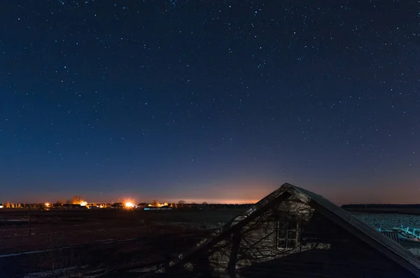 Blue and starry sky against the backdrop of the distant lights of the city — Stock Photo, Image