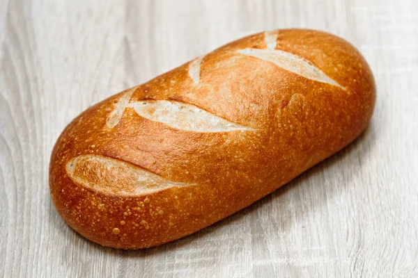 Freshly baked loaf on a light wooden background — Stock Photo, Image